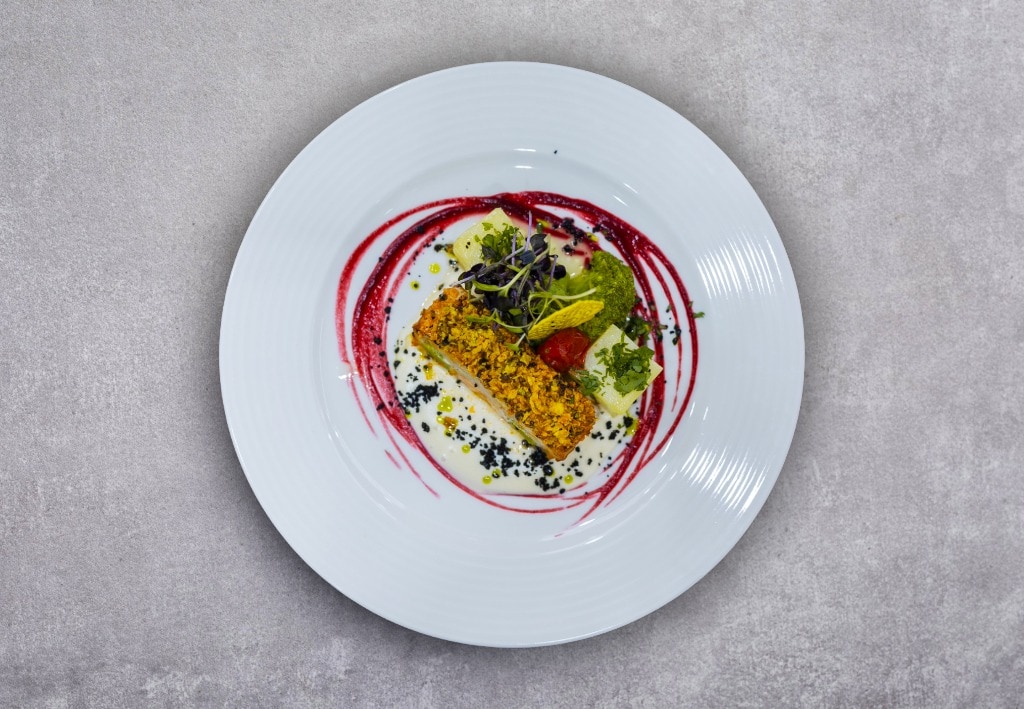 Ruladă de șalău aromatizat cu pesto roșu, în crustă de porumb și alune, servită cu sos de usturoi și garnitură de broccoli, roșii cherry sote și cartofi natur – - Reţetă