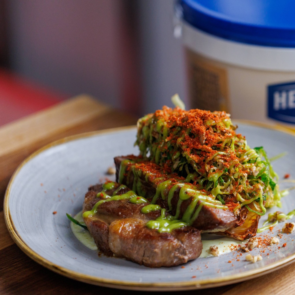 Steak de mangaliță cu varză confiată, crispy de praz și varză, emulsie de maioneză cu ulei de ierburi și maioneză verde
